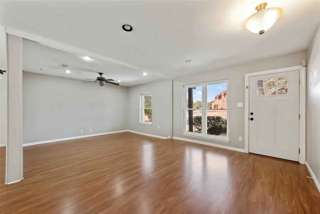 an empty room with wooden floor cabinet and windows