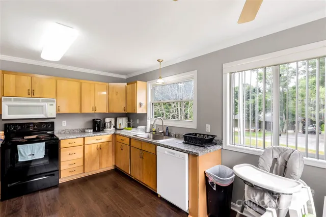 a kitchen with a sink appliances cabinets and a large window