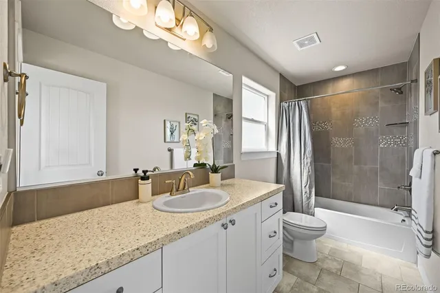 a bathroom with a granite countertop sink a toilet a mirror and shower