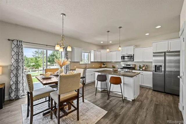 a kitchen with a dining table chairs and wooden floor