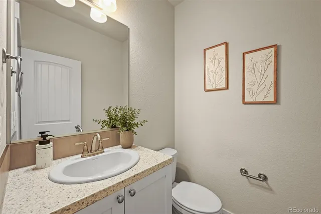 a bathroom with a granite countertop toilet sink and mirror