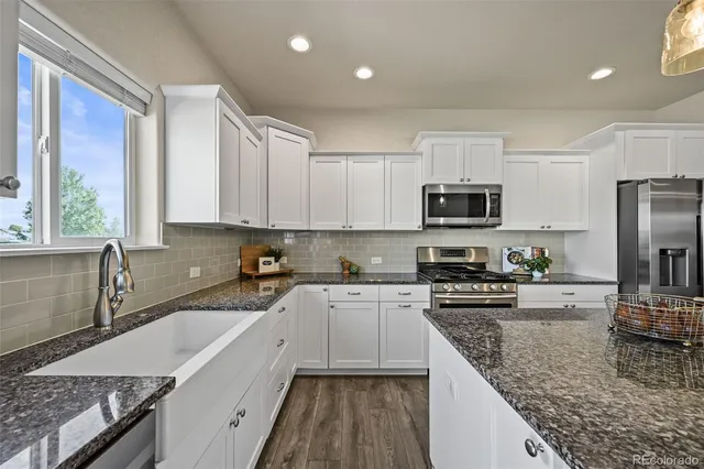 a kitchen with stainless steel appliances granite countertop a sink stove microwave and refrigerator