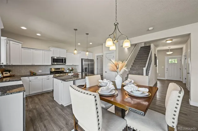 a kitchen with stainless steel appliances kitchen island granite countertop a stove a sink a dining table and chairs with wooden floor