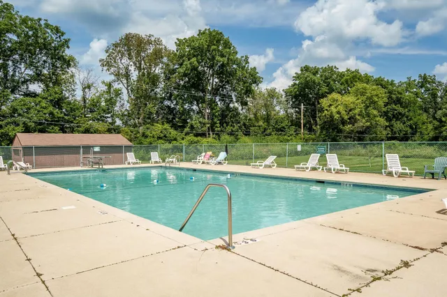 a view of a swimming pool with a lawn chairs under an umbrella