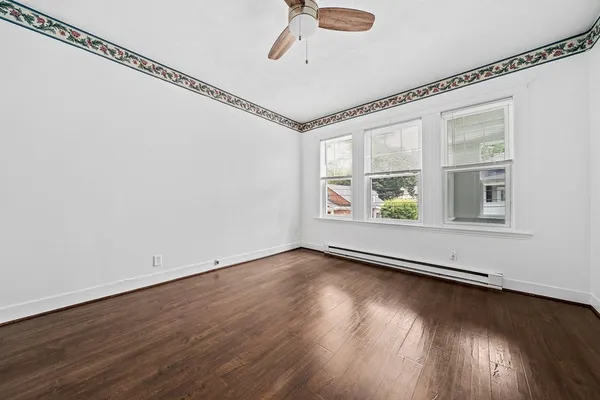 a view of an empty room with a window and wooden floor
