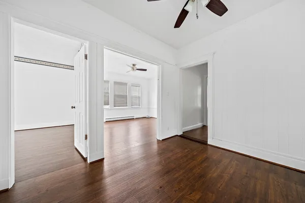 an empty room with wooden floor cabinet and windows
