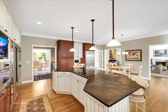 a kitchen with stainless steel appliances kitchen island granite countertop a table chairs and a view of living room
