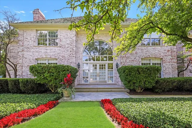 a view of a brick house with a yard and plants