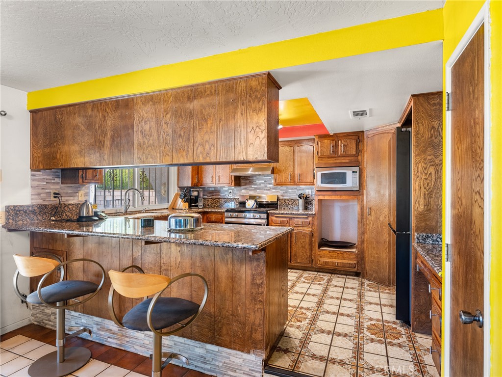 13916 Burning Tree Drive Victorville, CA 92395 - Photo 20 of 49 a kitchen with stainless steel appliances granite countertop a sink and cabinets