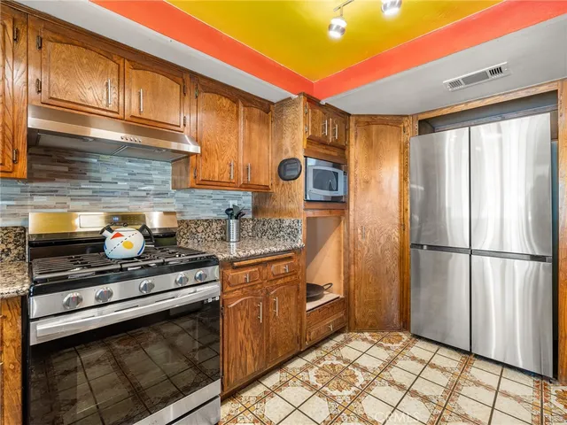 a kitchen with stainless steel appliances granite countertop a refrigerator a stove and a sink