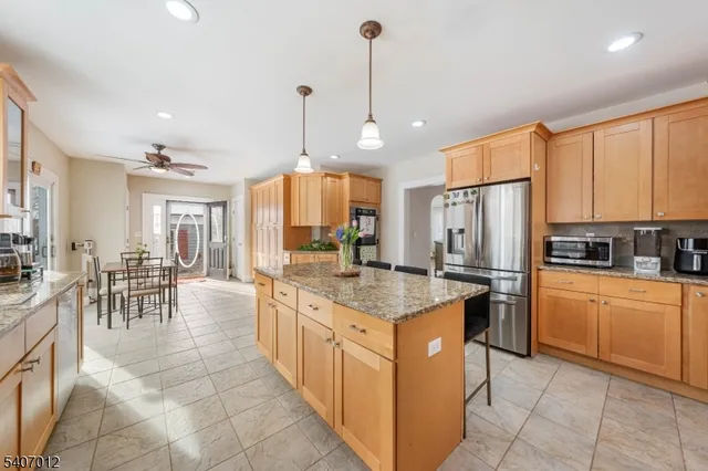 a kitchen with stainless steel appliances granite countertop table chairs and a refrigerator
