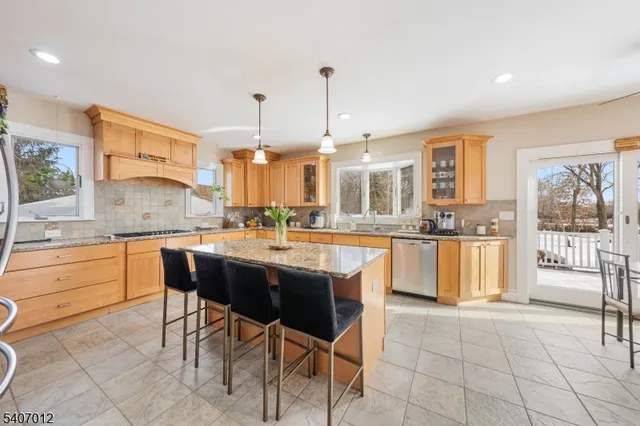 a large kitchen with granite countertop a stove a sink a dining table and chairs