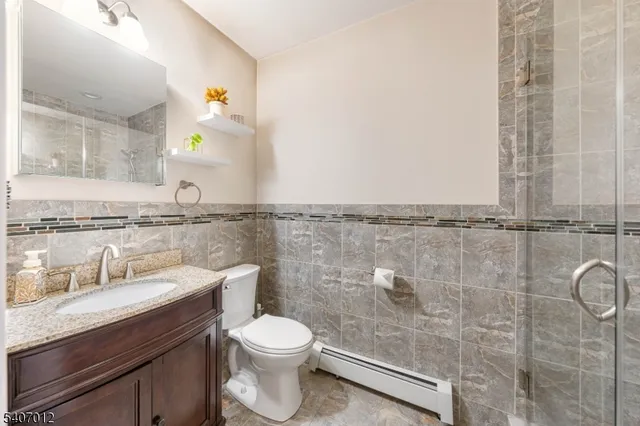 a bathroom with a granite countertop sink a toilet and shower