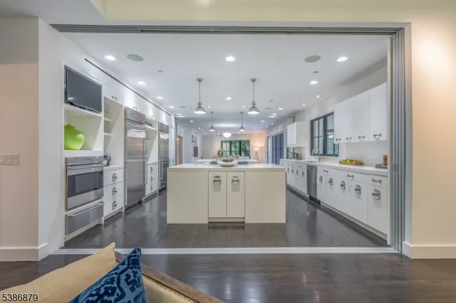 a view of a kitchen with kitchen island a counter top space a sink stainless steel appliances and cabinets