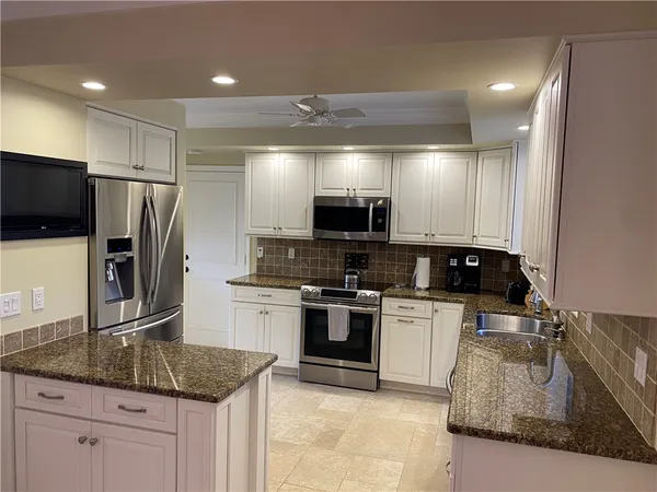 a kitchen with stainless steel appliances granite countertop a sink a stove top oven a refrigerator and a granite counter tops