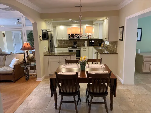 a dining room with stainless steel appliances kitchen island granite countertop a dining table chairs and a oven