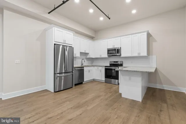 a kitchen with granite countertop a refrigerator and a stove top oven