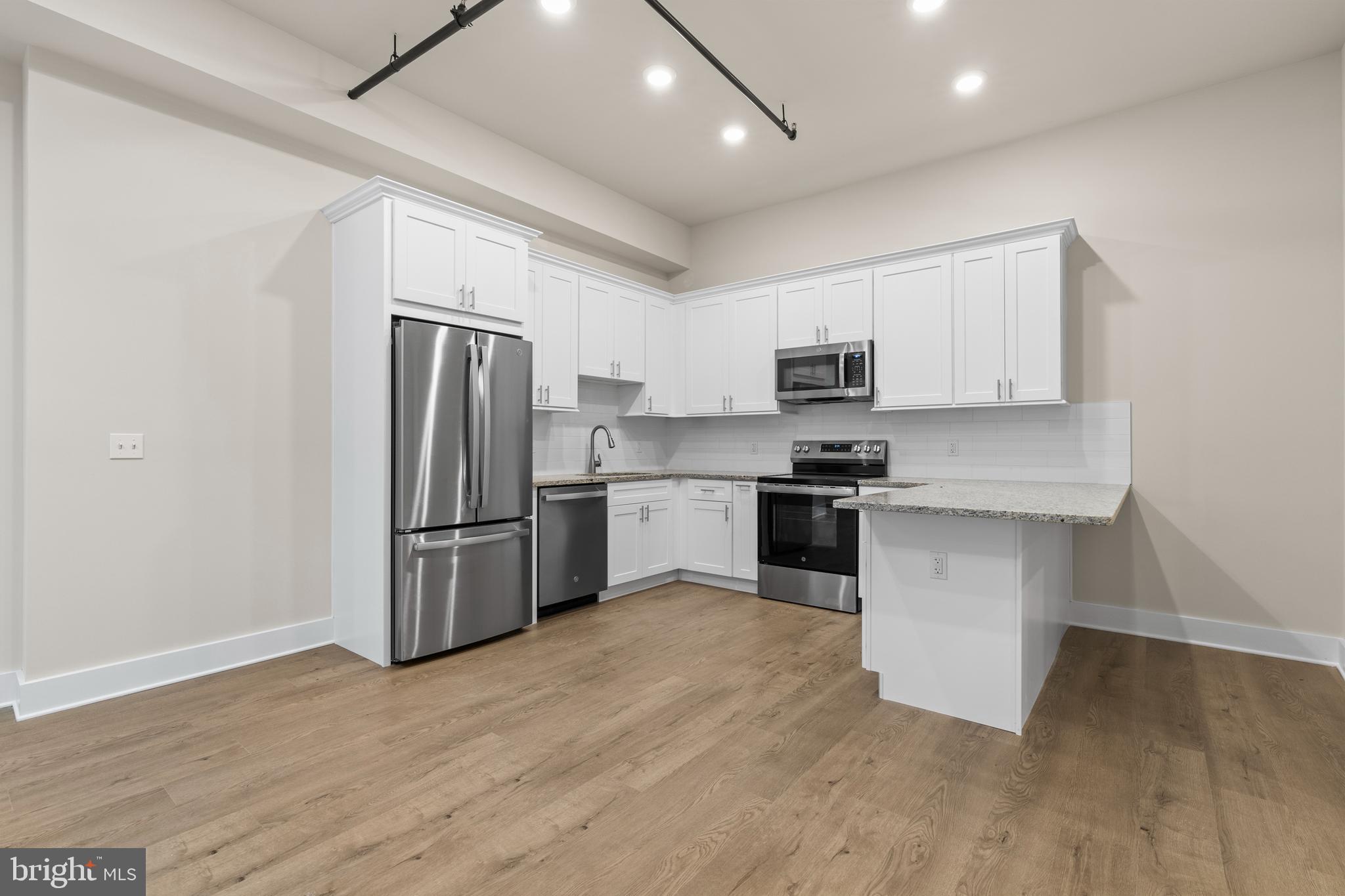 a kitchen with granite countertop a refrigerator and a stove top oven