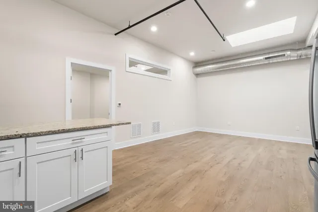 a view of a kitchen with white cabinets and wooden floor