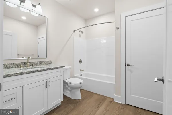 a bathroom with a granite countertop sink toilet a large mirror a bathtub and shower