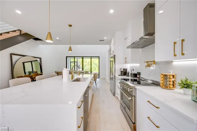 a large kitchen with kitchen island a stove a sink a refrigerator and wooden floor