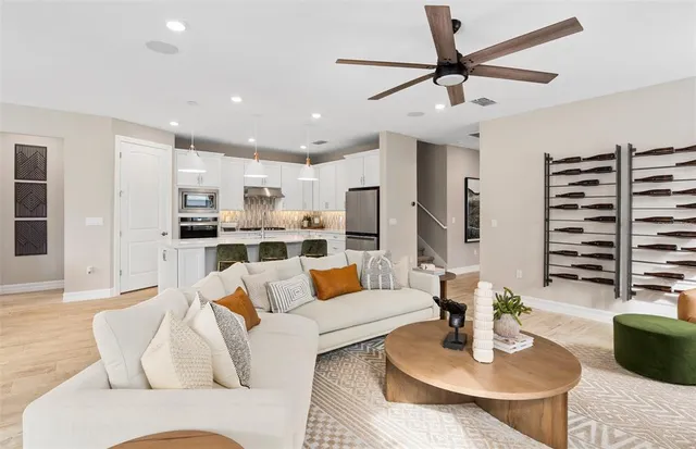 a living room with furniture kitchen view and a large window
