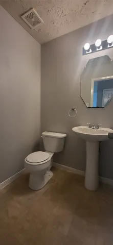 a white toilet sitting next to a bathroom sink and a mirror