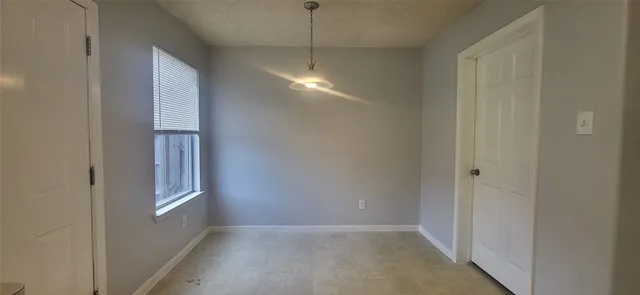 a view of an empty room with windows and chandelier