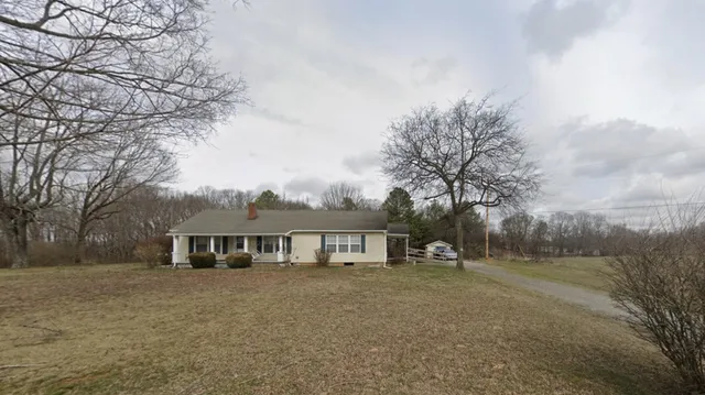 a front view of house with yard and trees in the background
