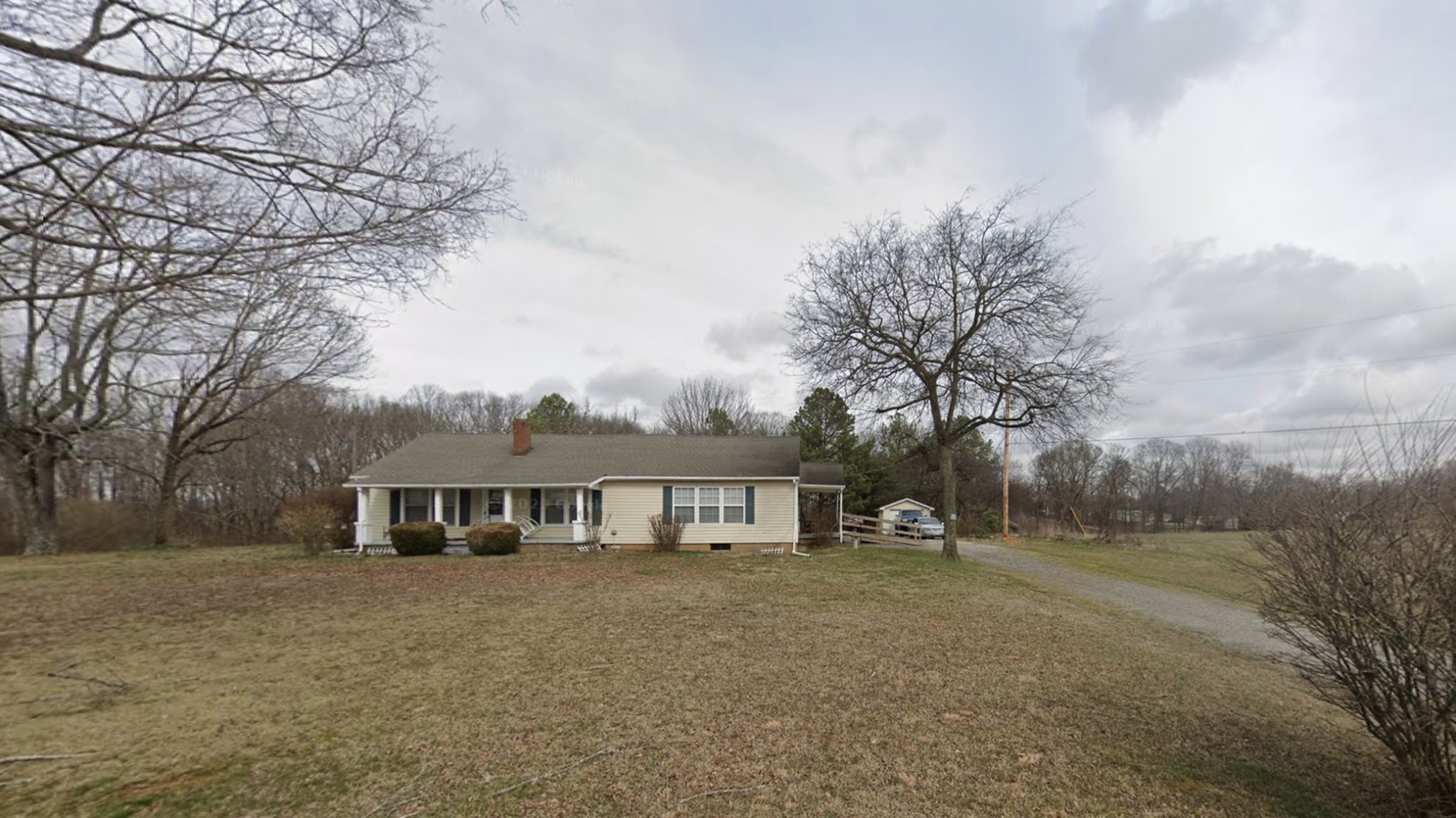 a front view of house with yard and trees in the background