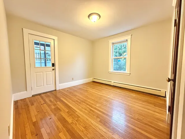 a view of an empty room with wooden floor and a window