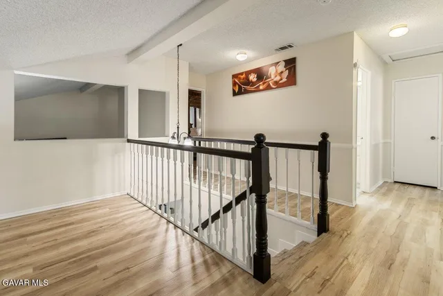 a view of a hallway with wooden floor and windows
