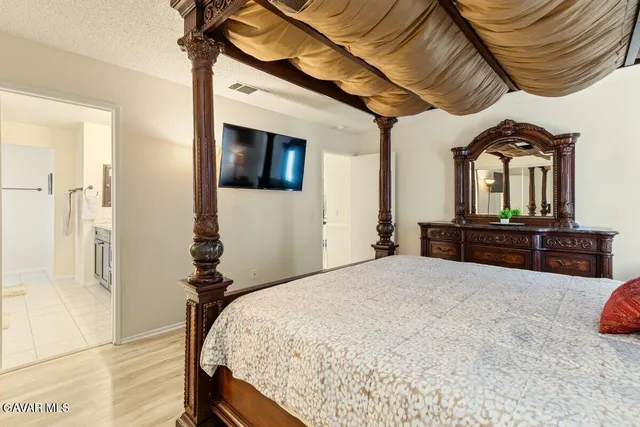 a spacious bedroom with a bed a dresser and potted plants