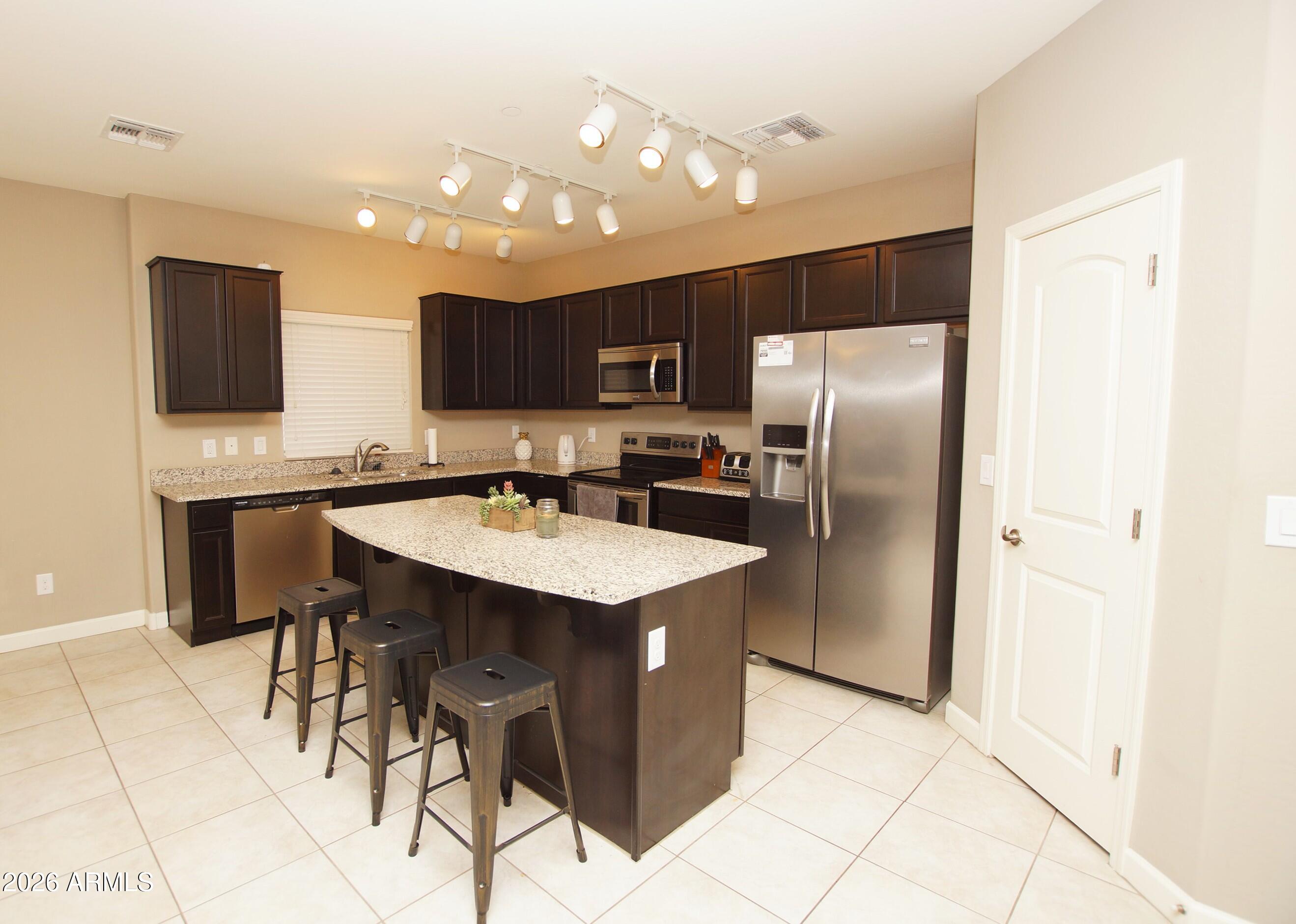 a kitchen with stainless steel appliances kitchen island granite countertop a refrigerator and a stove top oven