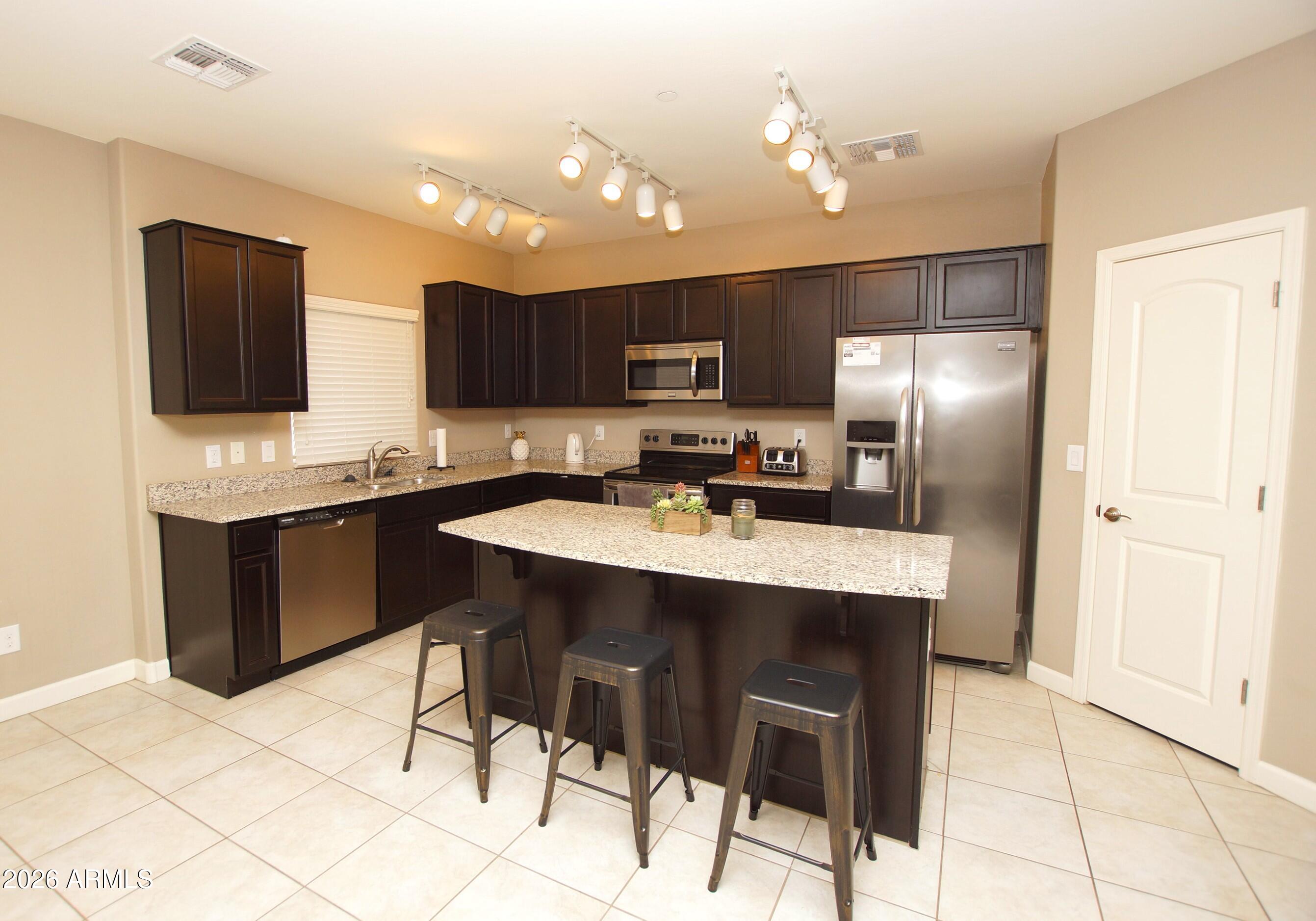 2150 West Alameda Road, Unit 1095 Phoenix, AZ 85085 - Photo 6 of 32 a kitchen with stainless steel appliances kitchen island granite countertop a sink cabinets and refrigerator
