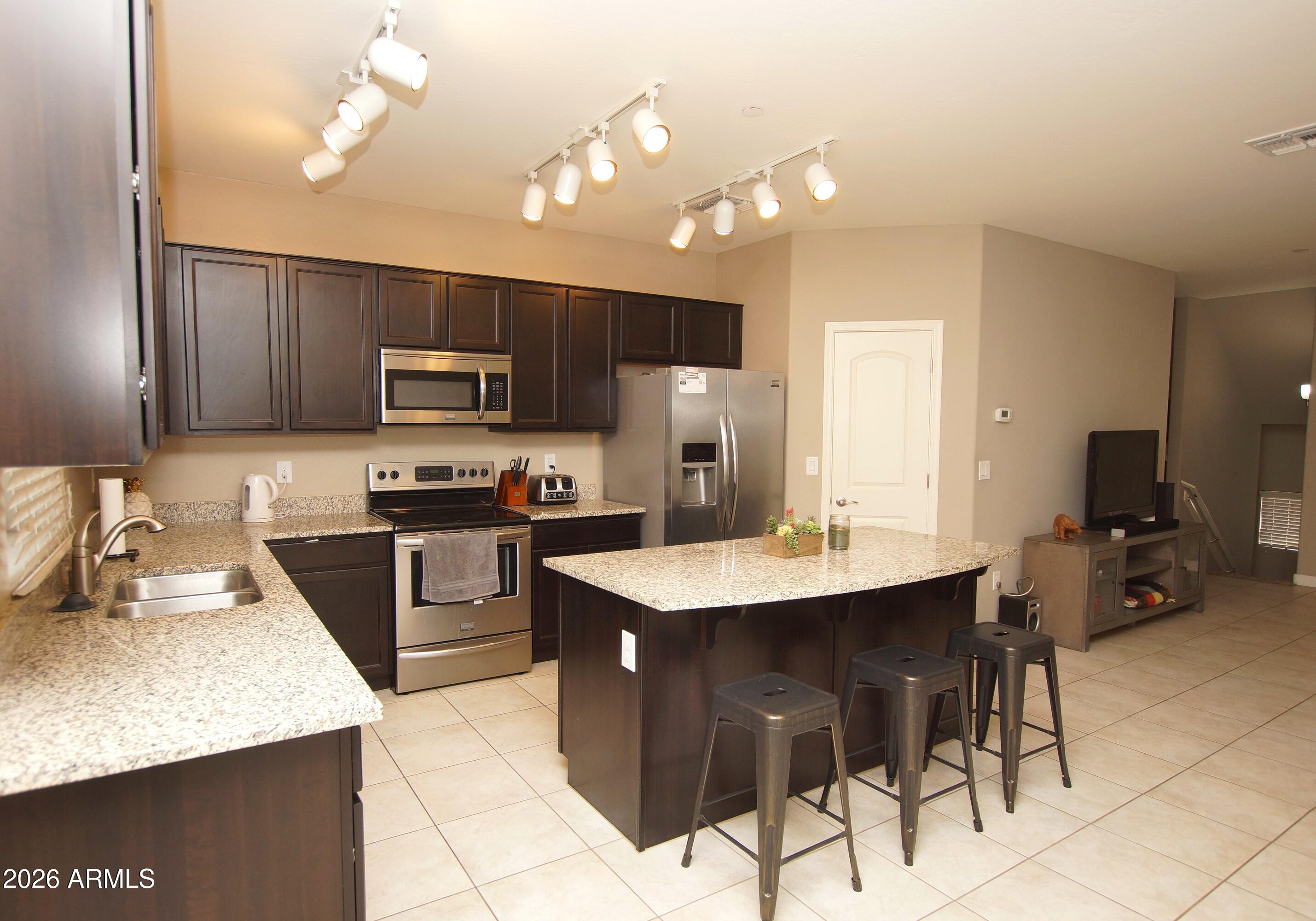 2150 West Alameda Road, Unit 1095 Phoenix, AZ 85085 - Photo 7 of 32 a kitchen with a sink a microwave and chairs
