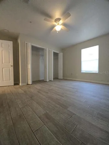 an empty room with windows and fan