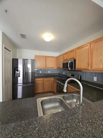 a kitchen with stainless steel appliances granite countertop a sink a stove and a refrigerator