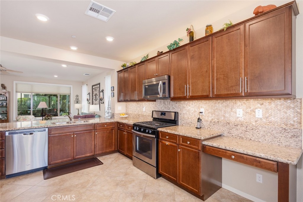 1370 Corte Alamonte Hemet, CA 92545 - Photo 11 of 62 a kitchen with stainless steel appliances granite countertop wooden cabinets a sink and dishwasher a stove top oven with wooden floor