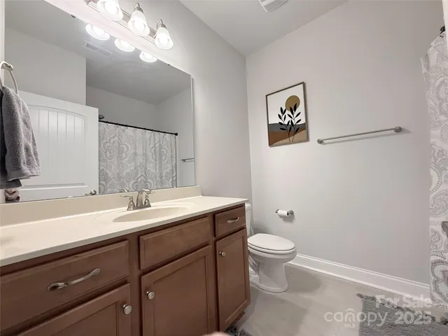 a bathroom with a granite countertop sink a toilet and a mirror