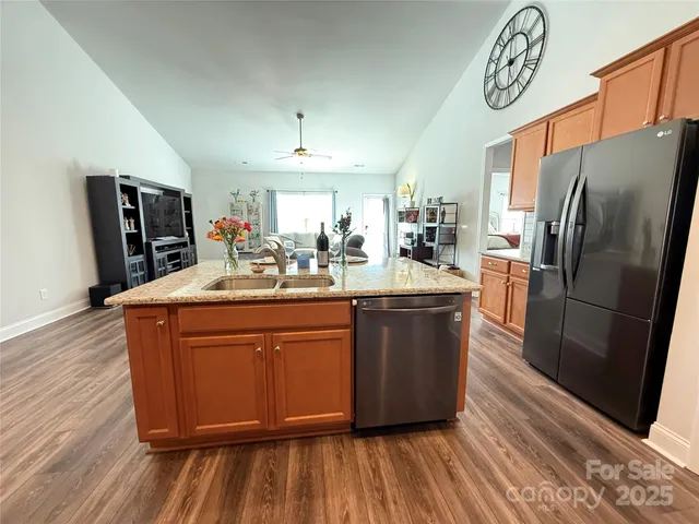 a kitchen with stainless steel appliances granite countertop a refrigerator a sink and wooden floor