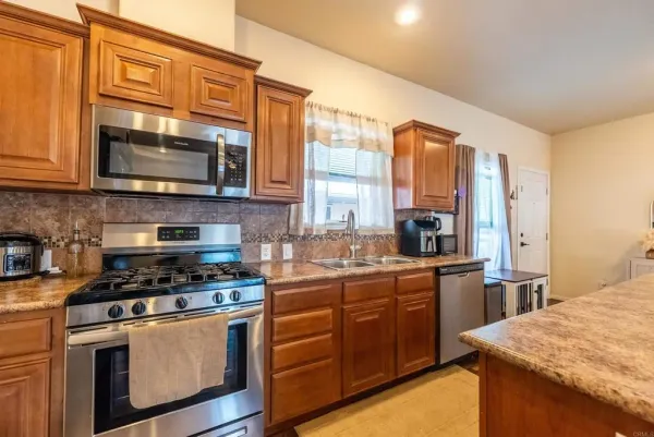 a kitchen with stainless steel appliances granite countertop a stove a sink and a microwave