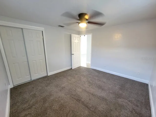 a view of an empty room and a chandelier fan