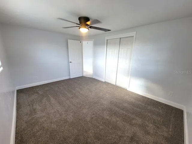 a view of an empty room with a chandelier fan