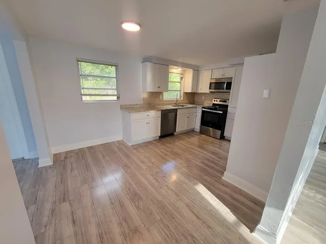 a kitchen with cabinets wooden floor and stainless steel appliances