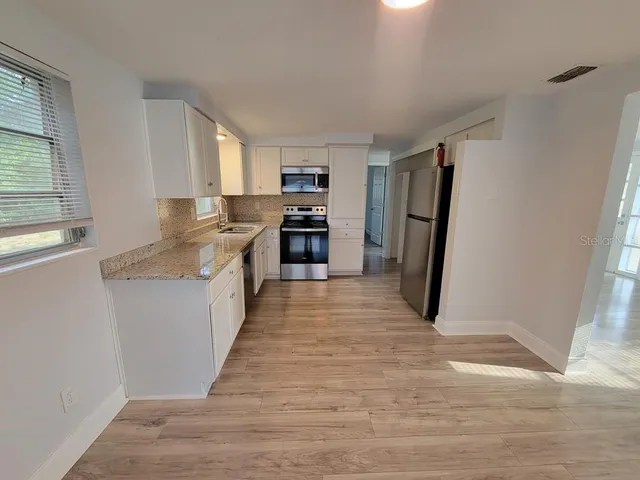 a kitchen with granite countertop a refrigerator and a sink