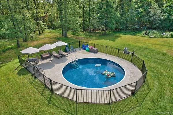 a view of a swimming pool and lounge chairs in back yard