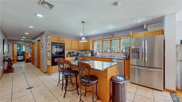 a kitchen with stainless steel appliances granite countertop a refrigerator a sink dishwasher a dining table and chairs with wooden floor