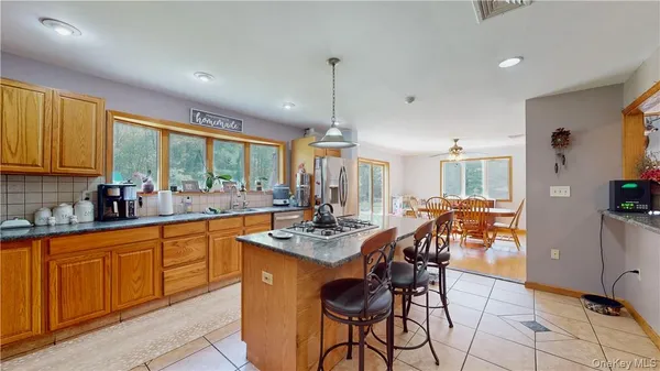 a dining hall with stainless steel appliances granite countertop a stove a sink a dining table and chairs with wooden floor