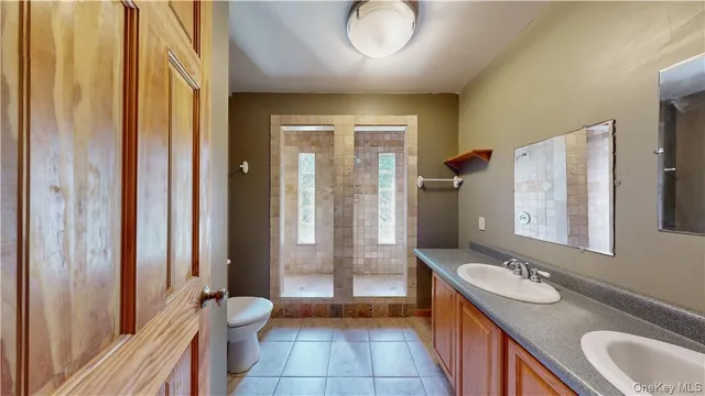 a bathroom with a granite countertop sink a toilet a mirror and shower